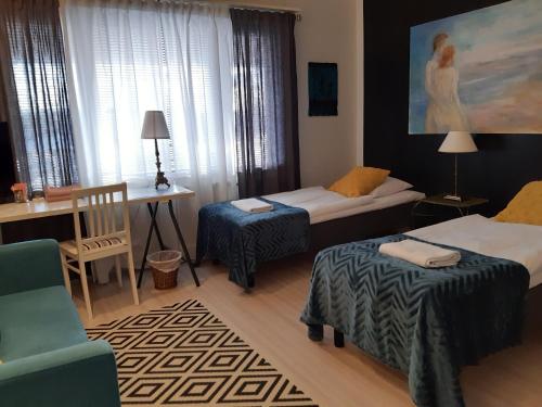 una camera con due letti e un tavolo e una sedia di Wanha Neuvola Guesthouse & Apartment a Pieksamaki