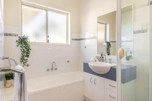 a bathroom with a white tub and a sink and a bath tubermott at A Wave From It All - Lennox Head in Lennox Head