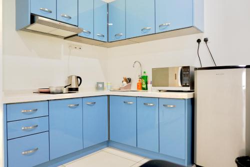 a kitchen with blue cabinets and a refrigerator at Gurney Drive Mansion One Serviced Apartment in George Town