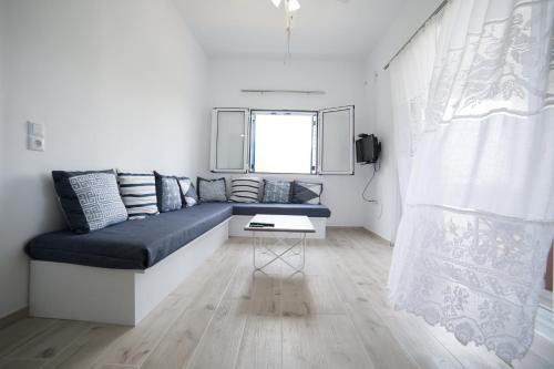Despinas house Kythnos في كيثنوس: غرفة معيشة مع أريكة زرقاء ونافذة