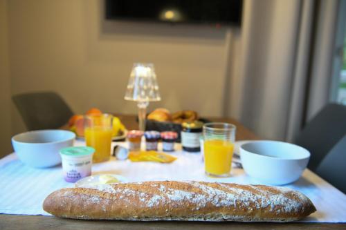 a table with a loaf of bread and cups of orange juice at Appart'Hotel Aiguille Verte & Spa in Chamonix-Mont-Blanc