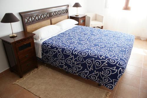 1 dormitorio con 1 cama con colcha azul y blanca en Alojamientos Botica Rural en La Cabrera
