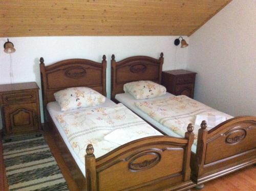 two beds in a room with a wooden headboard at Sarokhaz Panzio in Vecsés