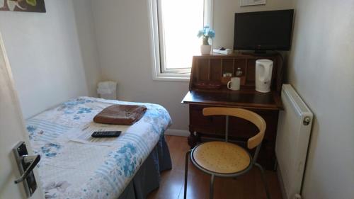 a small bedroom with a bed and a desk with a television at Tiny Single shared bathroom Room ssbyr in Hayes