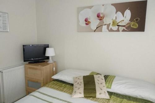 1 dormitorio con cama y vestidor con TV en Room in Guest room - Tiny Single shared bathroom Room ssbyr, en Hayes