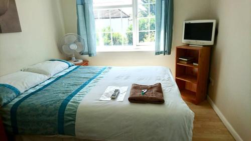 - une chambre avec un lit avec un sac et une télévision dans l'établissement Room in Guest room - Double with shared bathroom sleeps 1-2 located 5 minutes from Heathrow dsbyr, à Hayes