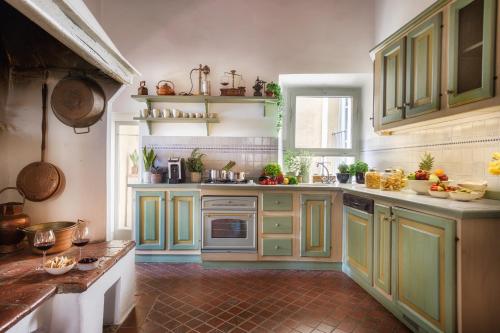 a kitchen with green cabinets and a red tile floor at Il Giardino del Cardinale - Deb'S Monticchiello in Monticchiello