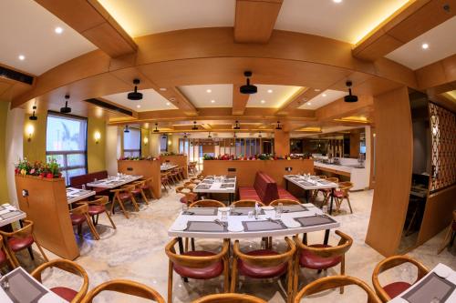 a dining room with tables and chairs at Lords Eco Inn Jamnagar - Apple Gate in Jamnagar