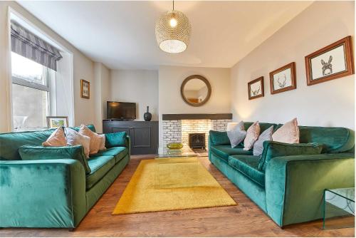 a living room with two green couches and a fireplace at Host & Stay - The Blacksmiths in Warkworth