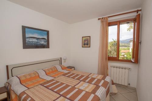 sypialnia z łóżkiem i oknem w obiekcie Casa Vacanze Lentisco by HelloElba w mieście Marina di Campo