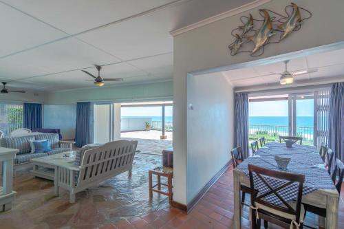 a dining room with a table and a living room with the ocean at 2C Edward Place in Ballito