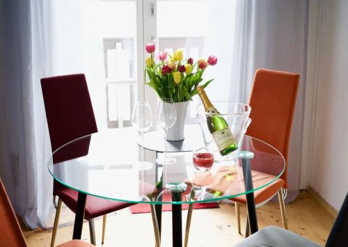 a glass table with a bottle of wine and a vase of flowers at Ferienwohnung Riesenblick in Frasdorf