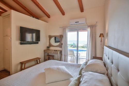 a bedroom with a bed and a television and a balcony at The White Chalet Boutique in Moshav Ramot
