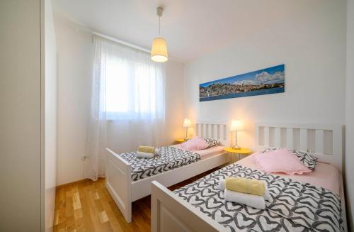 - 2 lits dans une petite chambre de couleur blanche et rose dans l'établissement Apartment Banjada, à Žaborić