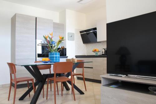 a dining room with a table and chairs and a television at Casa Mari in Villasimius