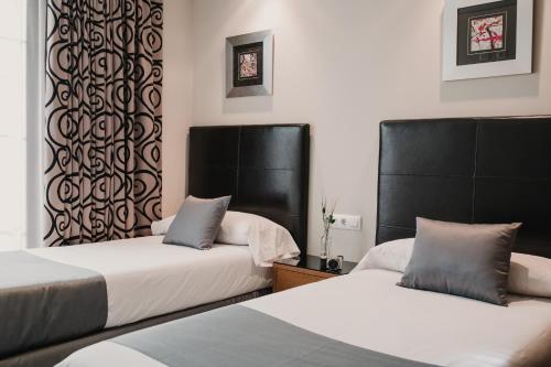 two beds with black headboards in a room at Citizentral Juristas in Valencia