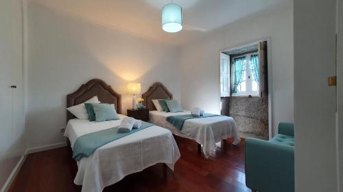 a room with two beds and a chair in it at Casa em Ponte de Lima in Ponte de Lima