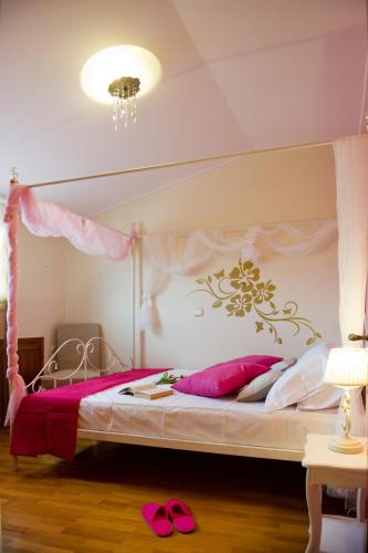 a bedroom with a canopy bed with pink pillows at LEFKAS CITY APARTMENTS & Suites in Lefkada Town
