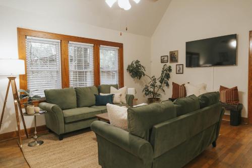a living room with two green couches and a television at The Woodlawn Tudor in Hot Springs