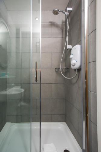 a shower with a glass door in a bathroom at Caring Hotel in London