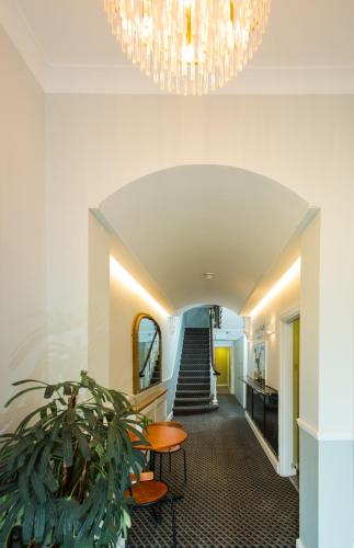a hallway with a potted plant and a chandelier at Caring Hotel in London