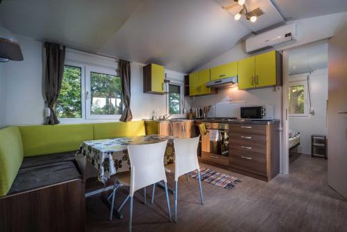 a kitchen with yellow cabinets and a table and chairs at Mara Camping Mobile Homes in Liptovský Trnovec