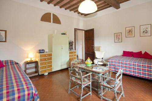 a bedroom with two beds and a table and a refrigerator at Villa di Montegemoli in Pomarance