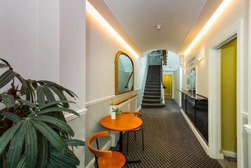 a hallway with a table and a plant and a staircase at Caring Hotel in London