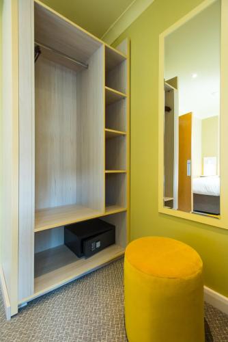 a room with a yellow stool and a mirror at Caring Hotel in London