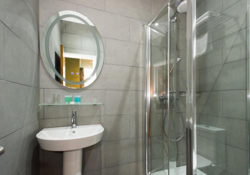 a bathroom with a sink, mirror, and shower at Caring Hotel in London