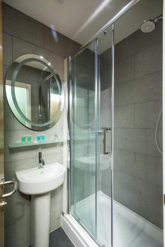 a bathroom with a glass shower and a sink at Caring Hotel in London