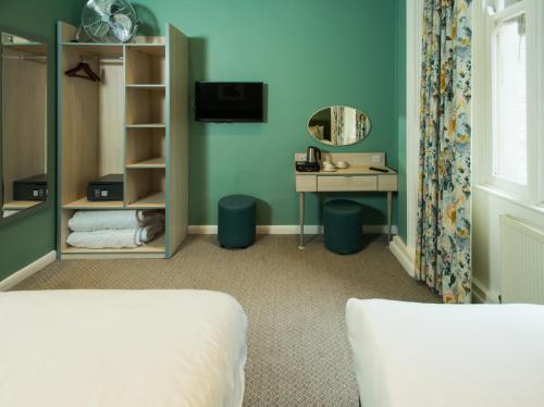 a bedroom with a bed and a desk and a mirror at Caring Hotel in London