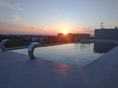 a pool on top of a building with the sunset at Salina Hotel in Taranto