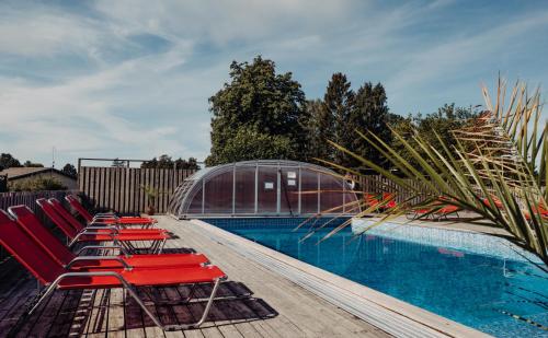 a row of red lounge chairs next to a swimming pool at Hotel Toftagården in Tofta