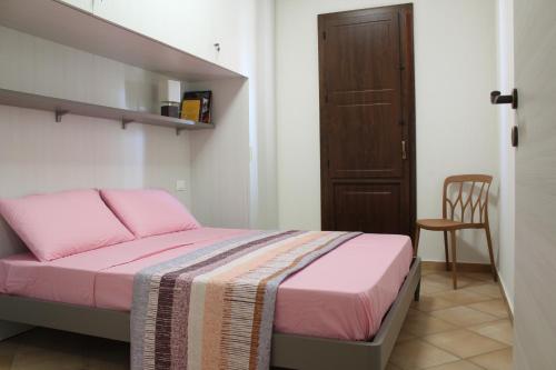 a small bedroom with a pink bed and a chair at Casa Mari in Villasimius