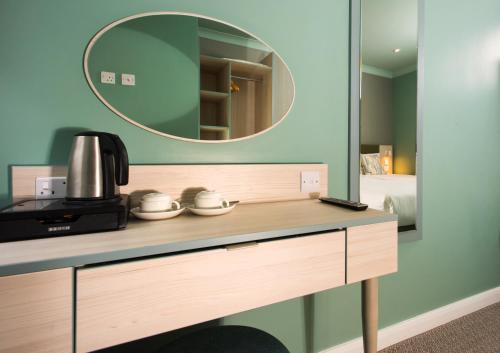 a counter with a mirror and a coffee maker on it at Caring Hotel in London