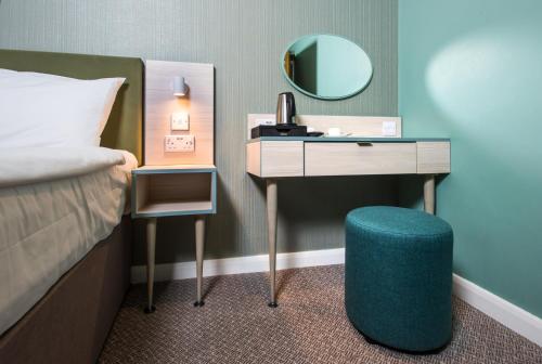 a bedroom with a bed and a desk with a mirror at Caring Hotel in London