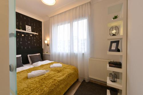 a bedroom with a bed with a yellow blanket at Királykút 2 apartman - ingyen parkolás, bicajok, ac in Székesfehérvár
