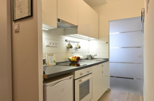 uma cozinha com armários brancos e um frigorífico branco em Királykút 2 apartman - ingyen parkolás, bicajok, ac em Székesfehérvár