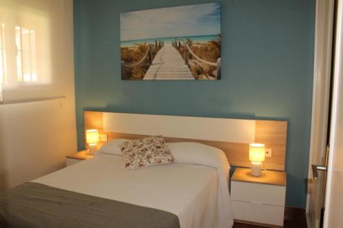 a bedroom with a bed and two lamps and a painting at Apartamentos Esteasur Islantilla in Islantilla