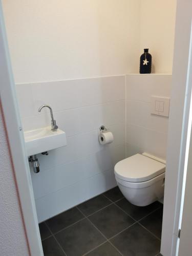 a white bathroom with a toilet and a sink at Housing De Brouwerij in Westdorpe