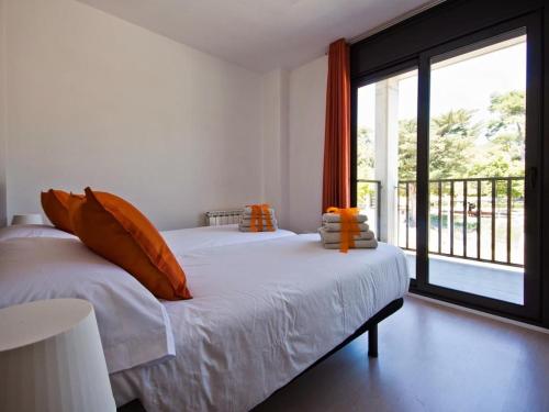 um quarto com uma cama com almofadas laranja e uma janela grande em Soho Parc em Figueres