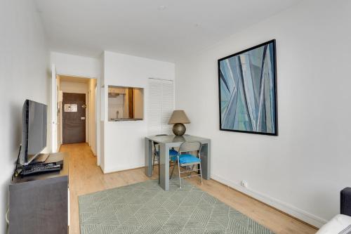 un salon avec un bureau et une table avec une télévision dans l'établissement ID 326 Batignolles/ rue Saussure - Paris XVII°, à Paris