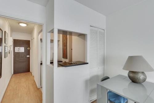 un couloir aux murs blancs et une table avec une lampe dans l'établissement ID 326 Batignolles/ rue Saussure - Paris XVII°, à Paris