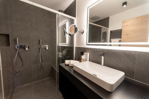 a bathroom with a sink and a shower at Penserhof - Alpine Hotel & Restaurant in Sarntal