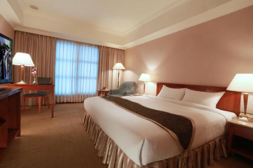a hotel room with a large bed and a television at Grand Boss Hotel in Yilan City