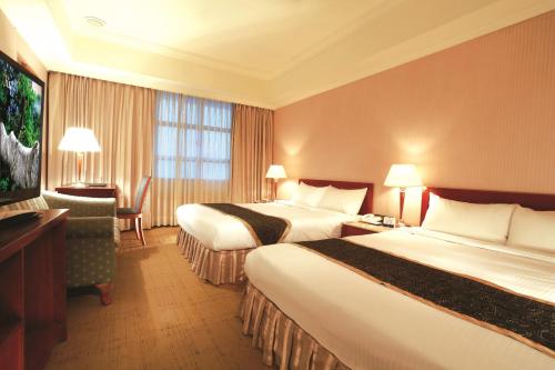 a hotel room with two beds and a flat screen tv at Grand Boss Hotel in Yilan City