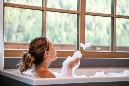 Eine Frau badet in einer Badewanne in der Unterkunft Penserhof - Alpine Hotel & Restaurant in Sarntal