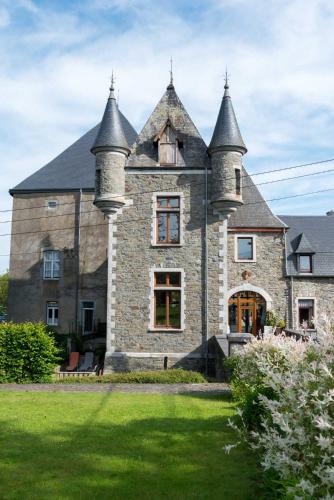 an old stone house with two towers on a lawn at Château Ferme de Laval in Sainte-Ode