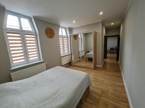 1 dormitorio con cama blanca y espejo en Ines Apartament en Ostrów Wielkopolski